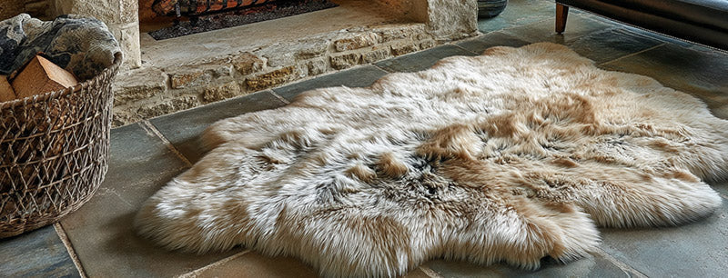 Large natural Sheepskin rug on the floor by the fireplace, stone walls
